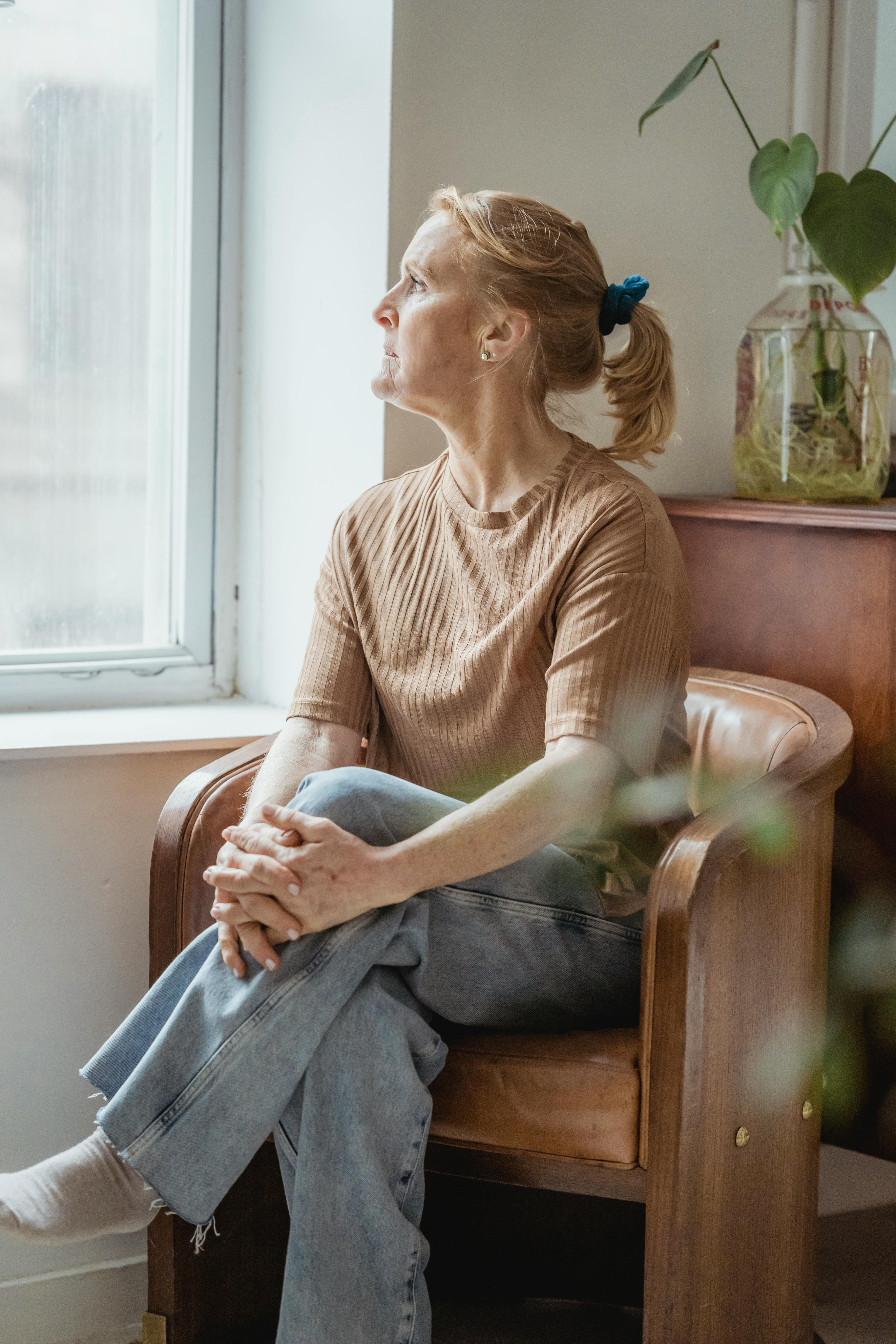 A woman sitting by a window in soft natural light.